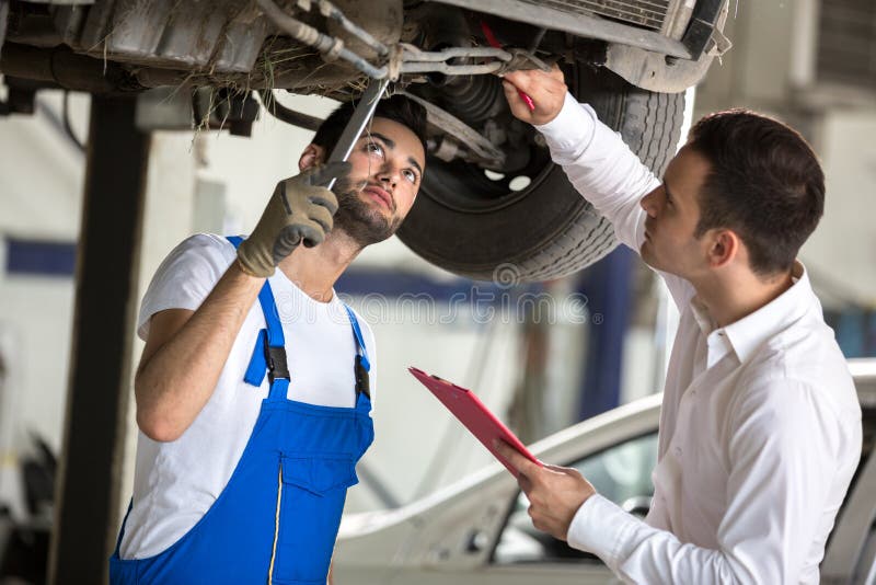 O assessor e o homem do reparo examinam o carro foto de stock O assessor e o homem do reparo examinam o carro foto de stock