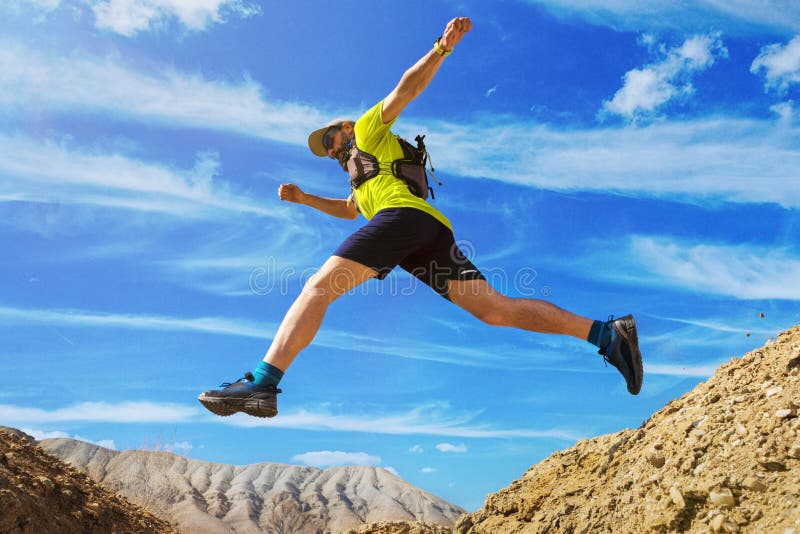 O atleta corre fora de estrada Saltos sobre uma ravina Corredor da fuga no deserto fotografia de stock O atleta corre fora de estrada Saltos sobre uma ravina Corredor da fuga no deserto fotografia de stock