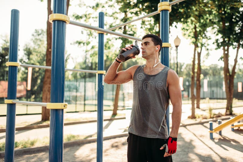 O atleta masculino bebe a água após o treinamento exterior fotos de stock O atleta masculino bebe a água após o treinamento exterior fotos de stock