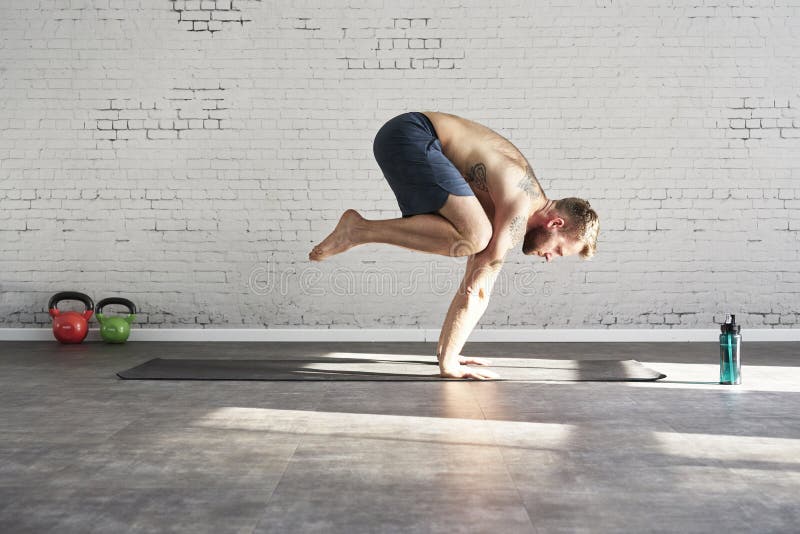 O atleta tattooed muscular que exercita o asana da ioga empurra acima para dentro o clube de esporte ensolarado Modelo masculino imagem de stock O atleta tattooed muscular que exercita o asana da ioga empurra acima para dentro o clube de esporte ensolarado Modelo masculino imagem de stock