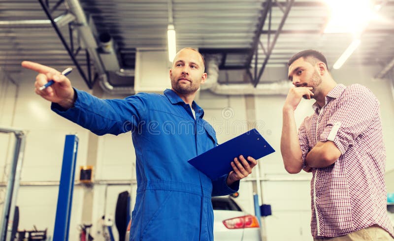 Auto service, repair, maintenance and people concept - mechanic with clipboard talking to men or owner at car shop. Auto service, repair, maintenance and people concept - mechanic with clipboard talking to men or owner at car shop