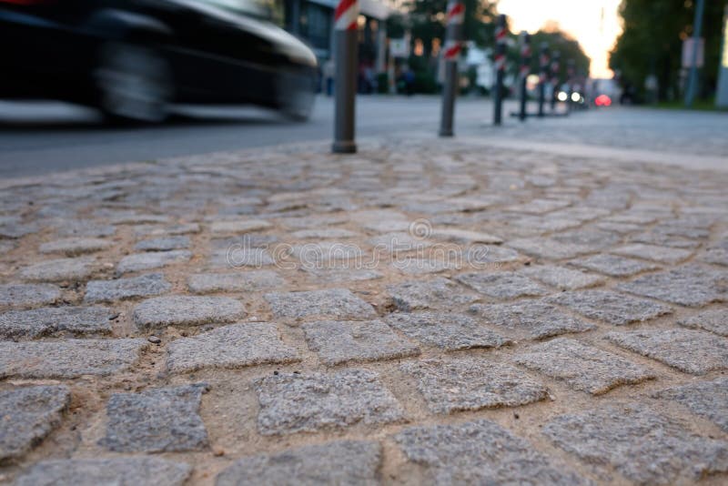 O baixo ângulo disparou de um sidwalk com pedras e carro fotografia de stock O baixo ângulo disparou de um sidwalk com pedras e carro fotografia de stock