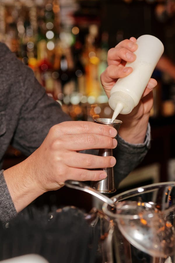 O barman está adicionando o ingrediente secreto no cocktail fotografia de stock O barman está adicionando o ingrediente secreto no cocktail fotografia de stock