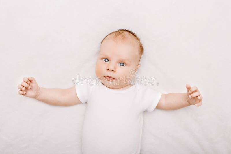 O bebê caucasiano branco engraçado adorável com cinza azul eyes o encontro na cama imagens de stock royalty free