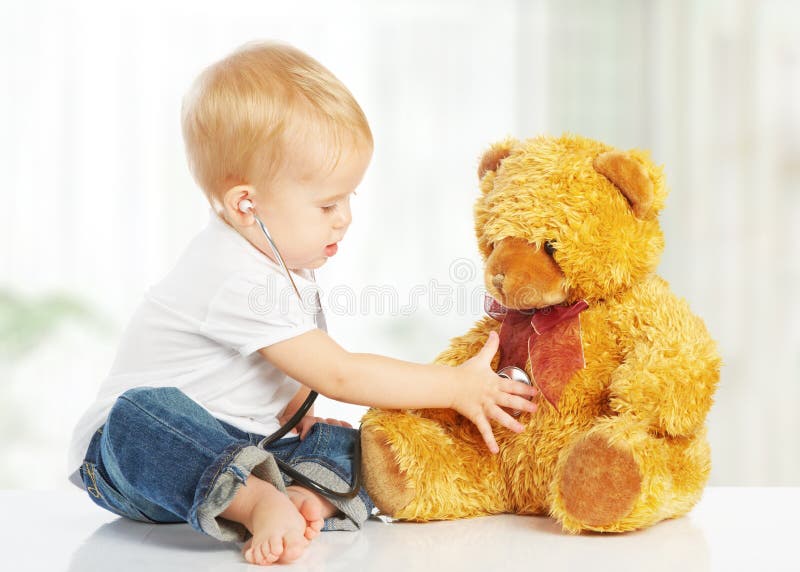 O bebê joga no urso de peluche do brinquedo do doutor e no estetoscópio imagem de stock royalty free O bebê joga no urso de peluche do brinquedo do doutor e no estetoscópio imagem de stock royalty free