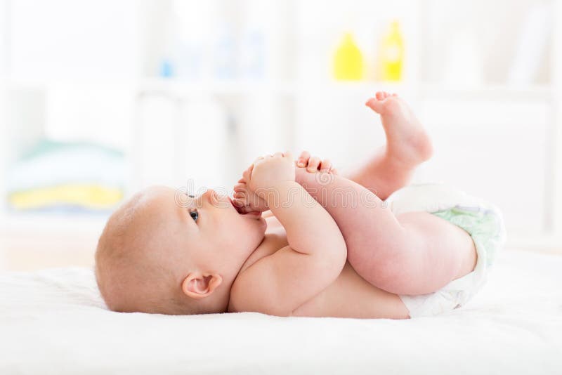 O bebê pequeno bonito weared o tecido que joga com seus pés e que suga em seu pé imagens de stock royalty free O bebê pequeno bonito weared o tecido que joga com seus pés e que suga em seu pé imagens de stock royalty free
