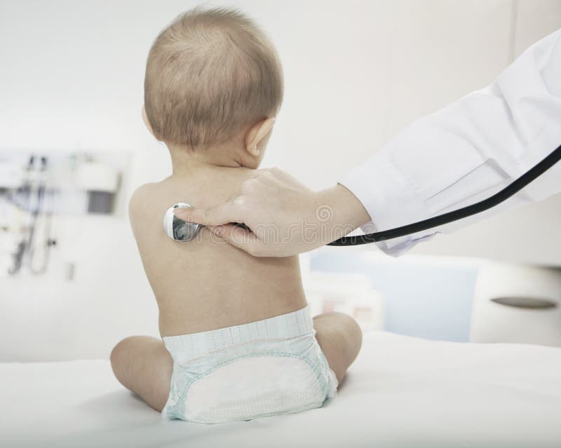 O bebê que senta-se no escritório dos doutores com os doutores entrega a verificação do batimento cardíaco com um estetoscópio imagem de stock O bebê que senta-se no escritório dos doutores com os doutores entrega a verificação do batimento cardíaco com um estetoscópio imagem de stock