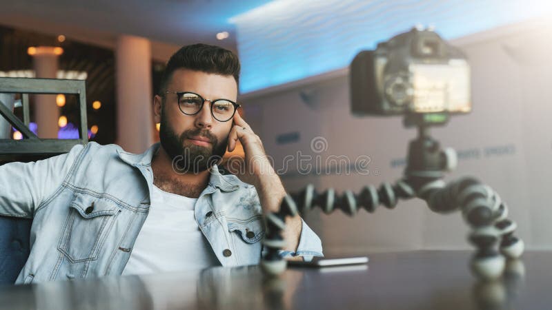 O blogger video masculino farpado novo cria o índice video para seu canal O indivíduo feliz dispara no vídeo que flui para usuári imagem de stock royalty free O blogger video masculino farpado novo cria o índice video para seu canal O indivíduo feliz dispara no vídeo que flui para usuári imagem de stock royalty free