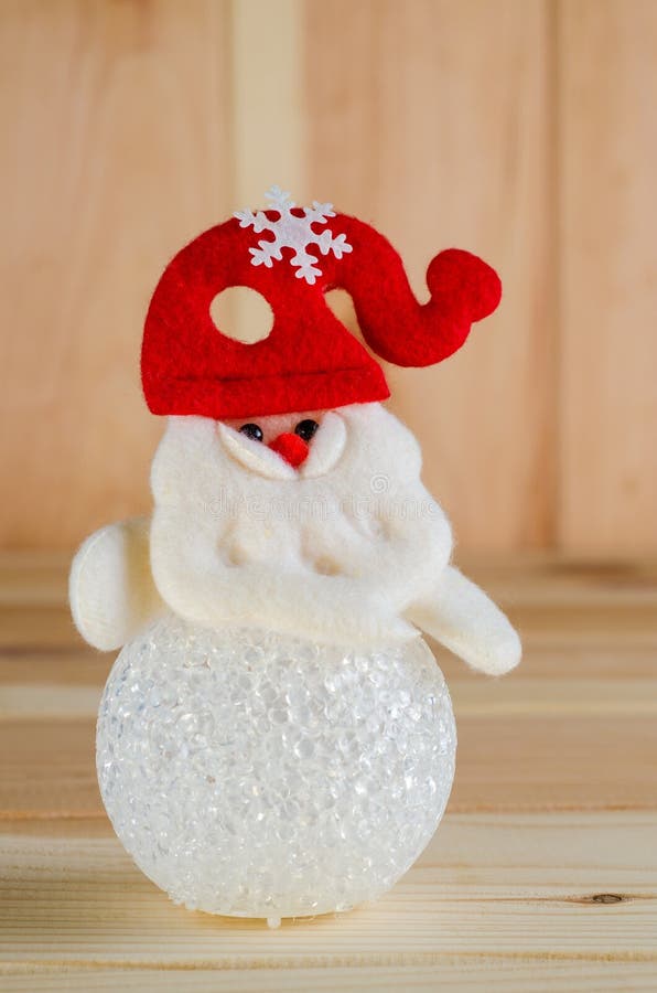 O boneco de neve do brinquedo em um chapéu vermelho é tiro luminoso grande em um fundo de madeira fotos de stock O boneco de neve do brinquedo em um chapéu vermelho é tiro luminoso grande em um fundo de madeira fotos de stock