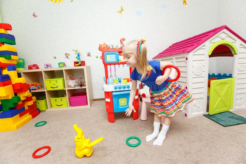 O brinquedo de jogo da menina loura consideravelmente pequena soa no jardim de infância imagem de stock O brinquedo de jogo da menina loura consideravelmente pequena soa no jardim de infância imagem de stock