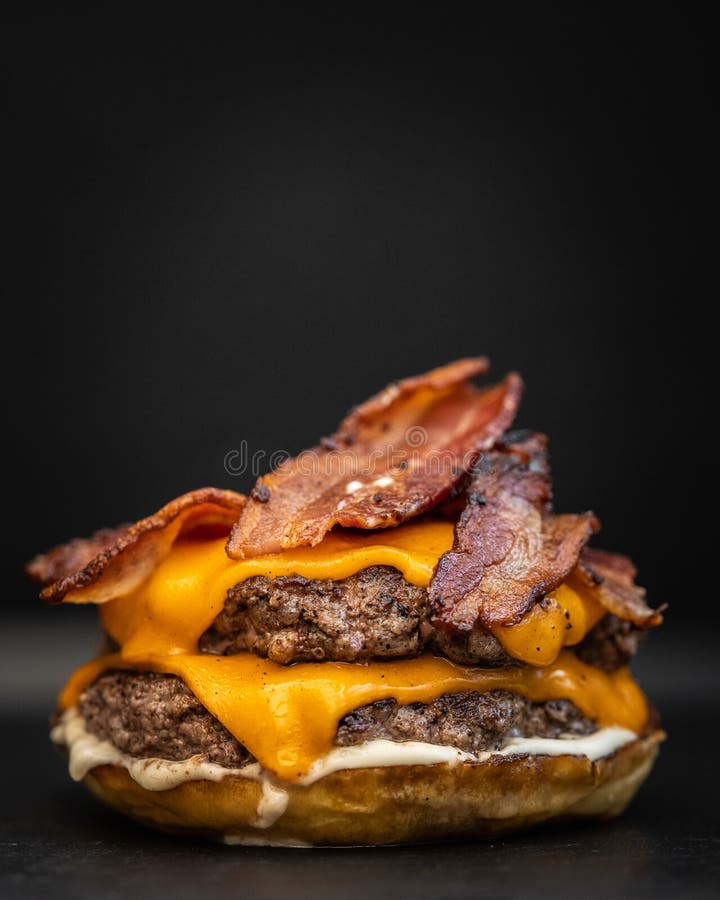 O bucată de carne dintr-un burger cu apă dulce cu șuncă topită și carne de vită stock images