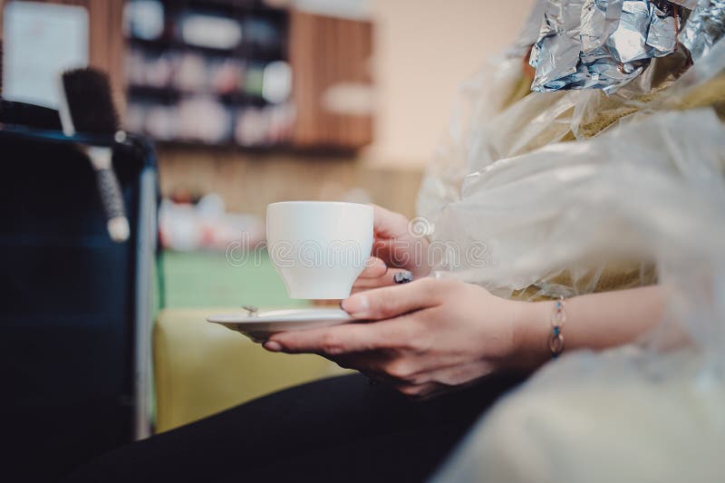 O cabeleireiro novo alegre está trançando o cabelo fêmea A mulher é de assento e bebendo o chá ou o café fotografia de stock royalty free O cabeleireiro novo alegre está trançando o cabelo fêmea A mulher é de assento e bebendo o chá ou o café fotografia de stock royalty free