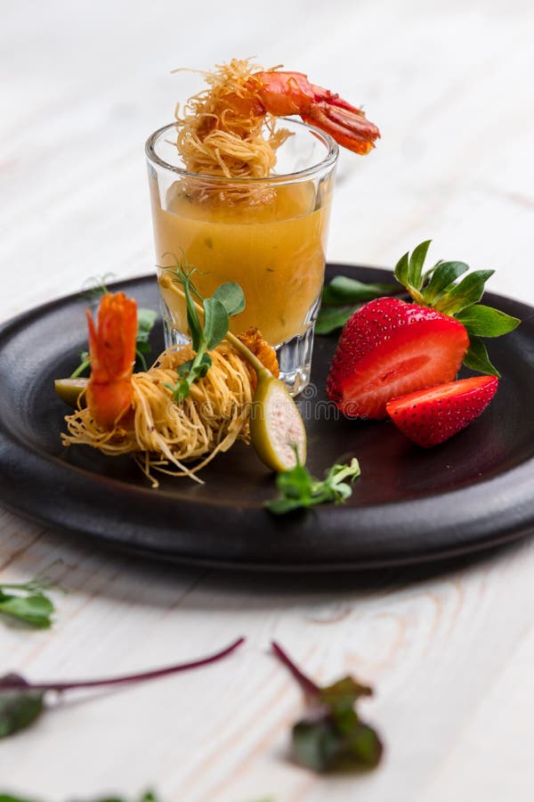 O camarão friável na crosta de Kataifi e o tomilho com Champagne Sauce nos vidros e nas morangos encontram-se em uma placa preta fotos de stock O camarão friável na crosta de Kataifi e o tomilho com Champagne Sauce nos vidros e nas morangos encontram-se em uma placa preta fotos de stock