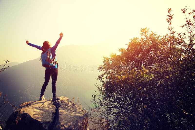 O caminhante Cheering da mulher abre os braços no pico de montanha fotografia de stock O caminhante Cheering da mulher abre os braços no pico de montanha fotografia de stock