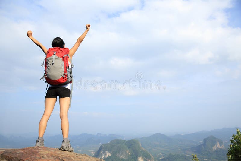 O caminhante Cheering da mulher abre os braços no pico de montanha imagem de stock O caminhante Cheering da mulher abre os braços no pico de montanha imagem de stock