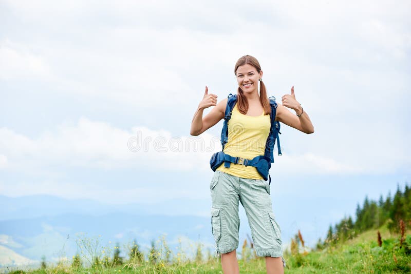 O caminhante da mulher que caminha no monte gramíneo, trouxa vestindo, usando trekking cola nas montanhas fotografia de stock O caminhante da mulher que caminha no monte gramíneo, trouxa vestindo, usando trekking cola nas montanhas fotografia de stock