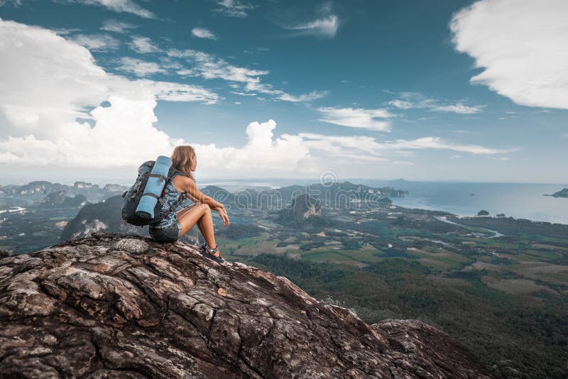O caminhante da mulher senta-se sobre uma montanha imagem de stock O caminhante da mulher senta-se sobre uma montanha imagem de stock