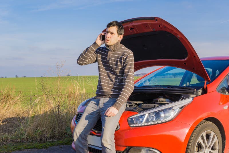 O carro é quebrado, homem está chamando o auxílio foto de stock O carro é quebrado, homem está chamando o auxílio foto de stock