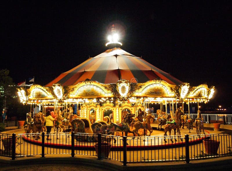 O carrossel em um parque de diversões na noite iluminou-se acima com luzes brilhantes