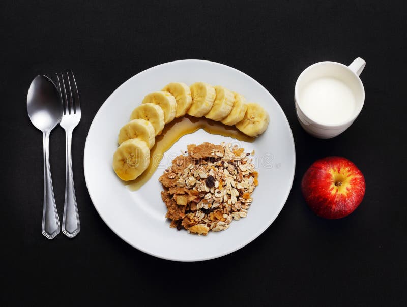 O cereal com banana cobriu com mel, leite e maçã à saúde fotografia de stock O cereal com banana cobriu com mel, leite e maçã à saúde fotografia de stock