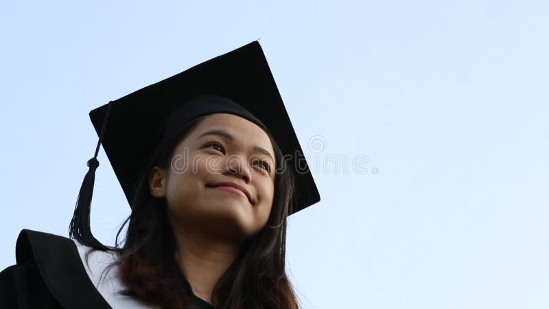 O chapéu de graduação é jogado no ar por uma garota asiática feliz no dia da formatura