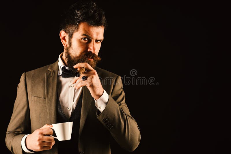 O chefe com barba fuma o charuto com xícara de café fotos de stock O chefe com barba fuma o charuto com xícara de café fotos de stock