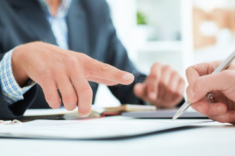 O chefe masculino recomenda que seu sinal do empregado um contrato no escritório O homem de negócio aponta ao lugar onde está imagem de stock royalty free O chefe masculino recomenda que seu sinal do empregado um contrato no escritório O homem de negócio aponta ao lugar onde está imagem de stock royalty free