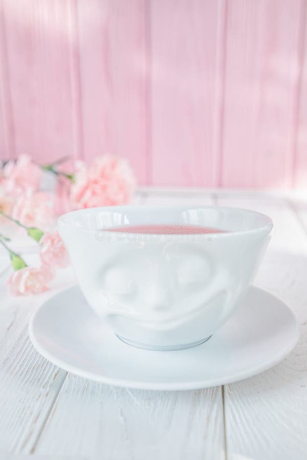 O chá do fruto no copo branco e no cravo cor-de-rosa floresce em um fundo branco Espaço livre foto de stock O chá do fruto no copo branco e no cravo cor-de-rosa floresce em um fundo branco Espaço livre foto de stock
