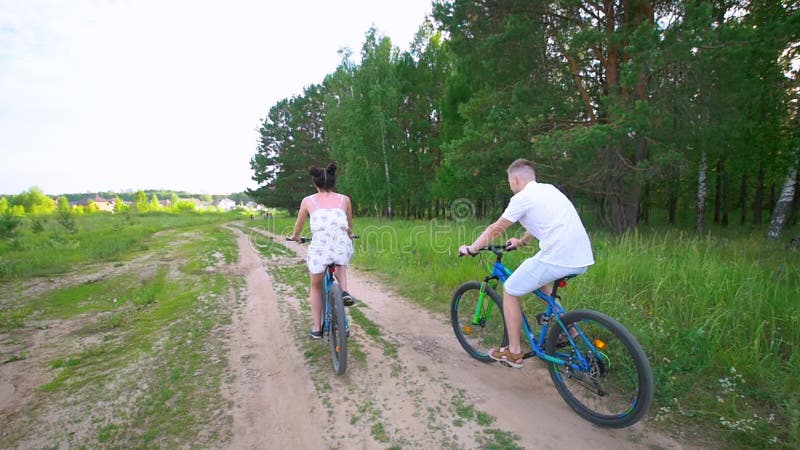 O ciclismo novo dos pares através do abeto vermelho ramifica na floresta do verão