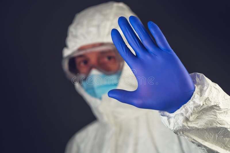 O cientista médico no vestuário de proteção que gesticula a parada assina dentro imagem de stock royalty free O cientista médico no vestuário de proteção que gesticula a parada assina dentro imagem de stock royalty free