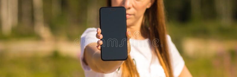 O close-up de um smartphone, uma menina está guardando um telefone na mão em um fundo borrado fotos de stock royalty free O close-up de um smartphone, uma menina está guardando um telefone na mão em um fundo borrado fotos de stock royalty free