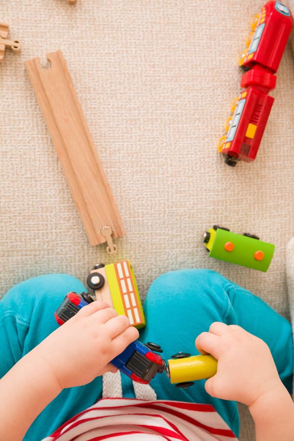 O close up do ` s da criança entrega o jogo com os brinquedos e a estrada de ferro de madeira do trem Vista superior Menino da cr fotografia de stock O close up do ` s da criança entrega o jogo com os brinquedos e a estrada de ferro de madeira do trem Vista superior Menino da cr fotografia de stock