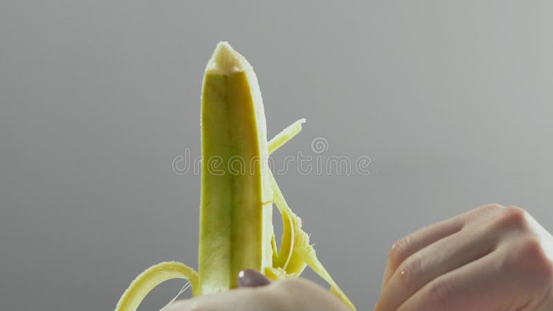 O close up, movimento lento, as mãos da mulher descasca a banana