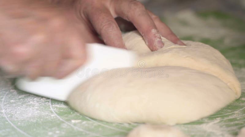 O close-up, ` s da mulher adulta entrega a fatia a massa plástica da faca em duas partes