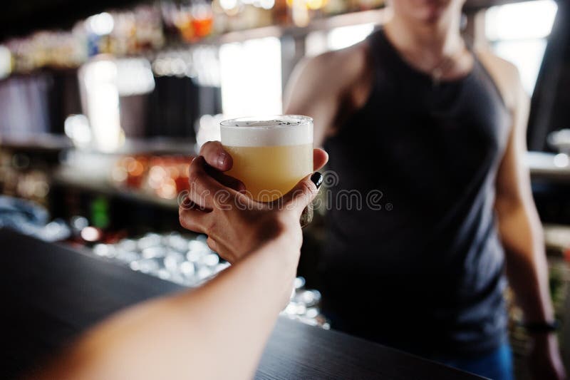 O cocktail alcoólico no vidro disponível do empregado de bar dá o cliente ao Dr. fotografia de stock O cocktail alcoólico no vidro disponível do empregado de bar dá o cliente ao Dr. fotografia de stock