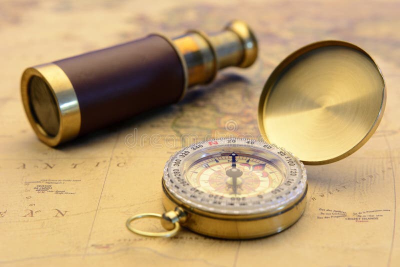 O compasso de bronze e o telescópio velho no vintage traçam o conceito do explorador do mundo