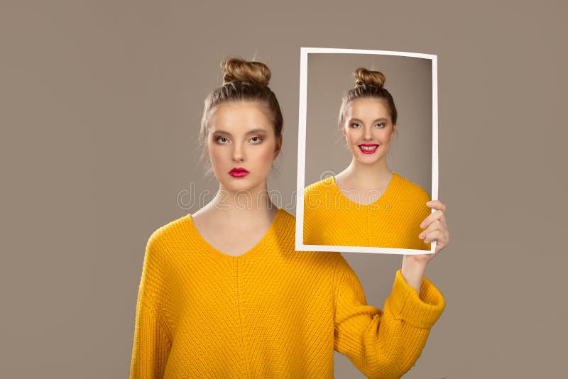 The concept of hypocrisy. Duplicity. The girl holds and changes face with portraits with different emotions. The concept of hypocrisy. Duplicity. The girl holds and changes face with portraits with different emotions