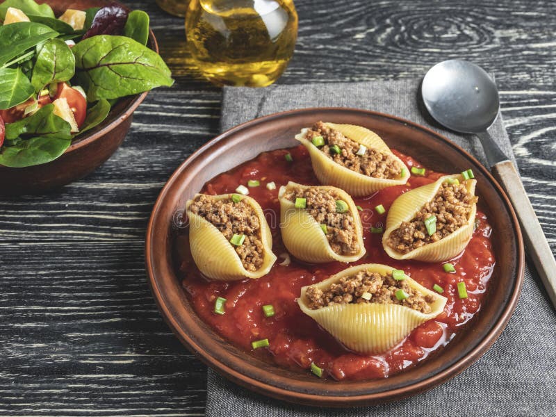 O conchiglioni cozinhado da massa encheu a carne triturada, molho de tomate na placa foto de stock O conchiglioni cozinhado da massa encheu a carne triturada, molho de tomate na placa foto de stock