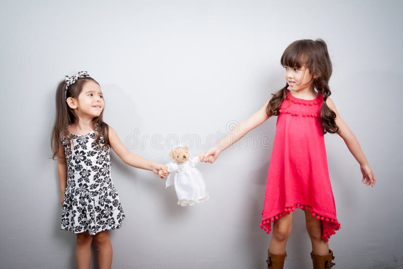O conflito entre duas irmãs as crianças estão lutando, luta sobre para o brinquedo imagem de stock royalty free O conflito entre duas irmãs as crianças estão lutando, luta sobre para o brinquedo imagem de stock royalty free