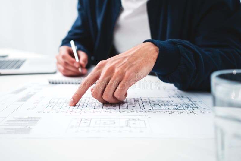 O coordenador do homem que olha o quando do desenho e do computador senta-se pela tabela no escritório do sótão fotos de stock royalty free O coordenador do homem que olha o quando do desenho e do computador senta-se pela tabela no escritório do sótão fotos de stock royalty free