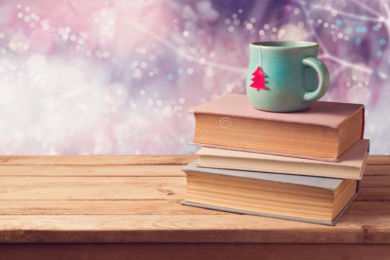 Christmas cup of tea and vintage books on wooden table over dreamy beautiful winter bokeh background with copy space. Christmas cup of tea and vintage books on wooden table over dreamy beautiful winter bokeh background with copy space