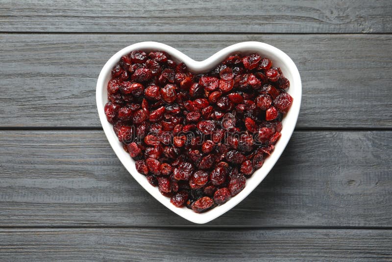 Heart shaped bowl with cranberries on wooden background, top view. Dried fruit as healthy snack. Heart shaped bowl with cranberries on wooden background, top view. Dried fruit as healthy snack