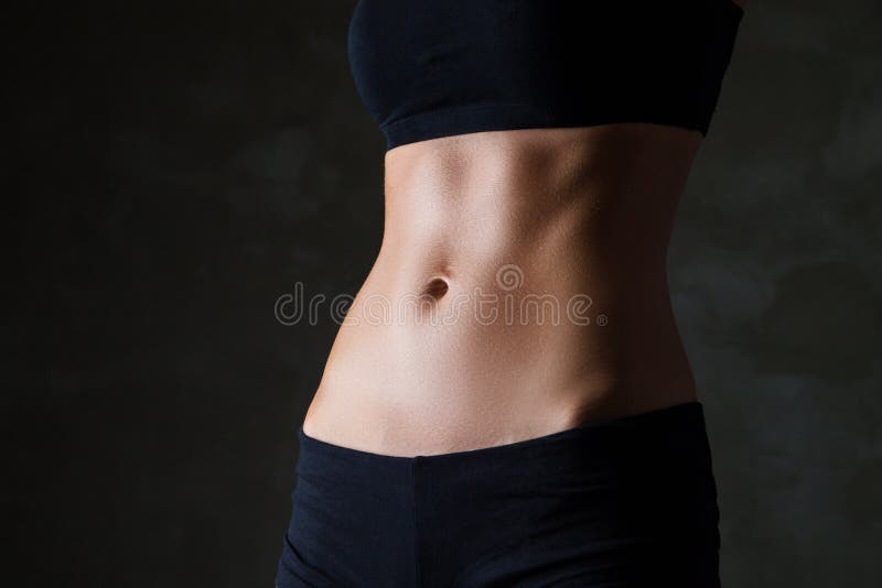 O corpo magro da mulher sobre o fundo cinzento escuro imagem de stock O corpo magro da mulher sobre o fundo cinzento escuro imagem de stock