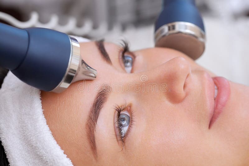 O cosmetologist faz ao procedimento uma limpeza ultrassônica da pele facial fotos de stock O cosmetologist faz ao procedimento uma limpeza ultrassônica da pele facial fotos de stock
