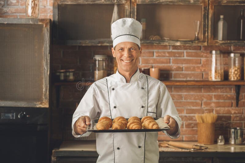 O cozimento do cozinheiro chefe da padaria coze no profissional da cozinha fotografia de stock royalty free O cozimento do cozinheiro chefe da padaria coze no profissional da cozinha fotografia de stock royalty free