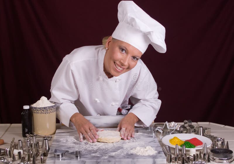O cozinheiro chefe da pastelaria dá forma à massa de pão do bolinho imagens de stock royalty free O cozinheiro chefe da pastelaria dá forma à massa de pão do bolinho imagens de stock royalty free