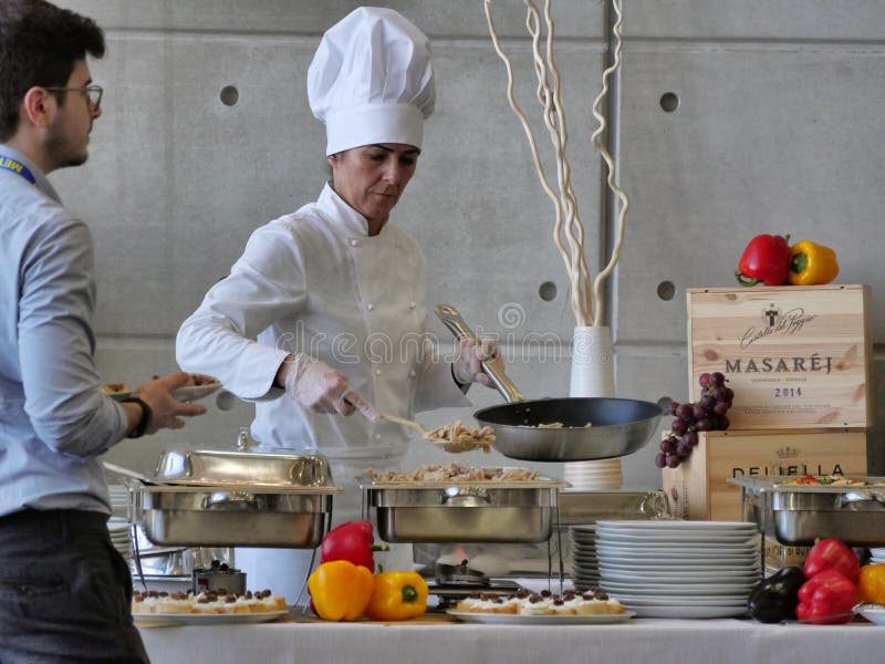 O cozinheiro chefe f?mea profissional prepara o alimento do bufete para clientes imagem de stock O cozinheiro chefe f?mea profissional prepara o alimento do bufete para clientes imagem de stock
