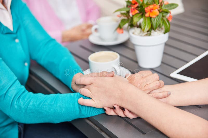 O cuidador dá a mão de um idoso ao conforto