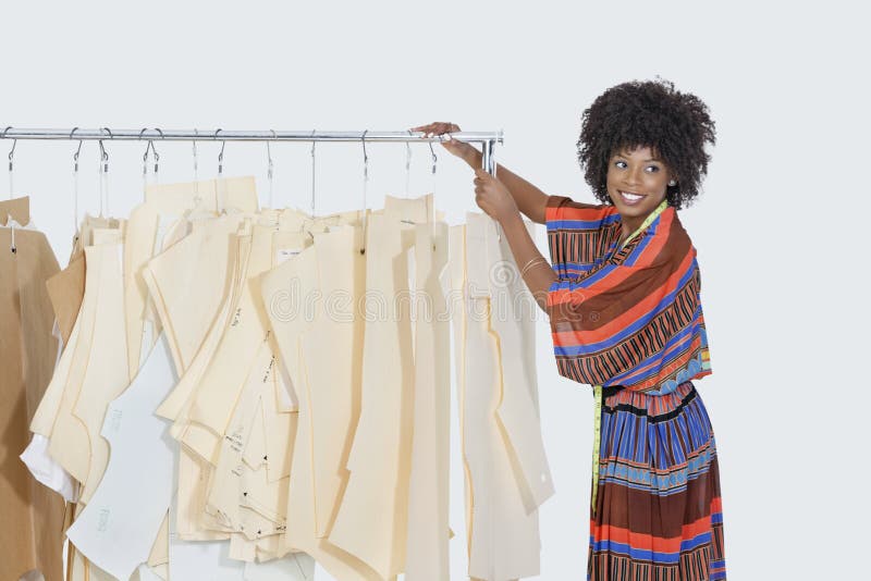 O desenhista fêmea afro-americano com testes padrões da costura na roupa submete sobre o fundo cinzento fotografia de stock O desenhista fêmea afro-americano com testes padrões da costura na roupa submete sobre o fundo cinzento fotografia de stock