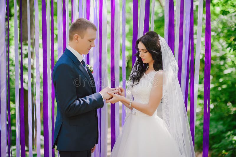 O desgaste dos noivos em uma cerimônia de casamento quando anéis em um fundo de fitas multi-coloridas, amor, união, rel